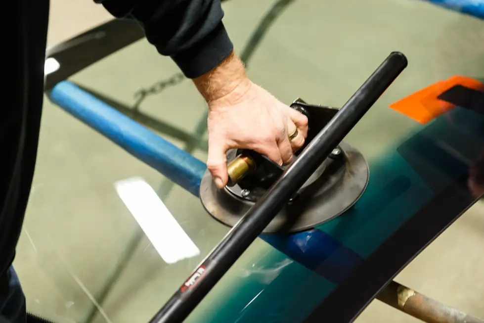 Technician setting a suction cup handle on a windshield before lifting it